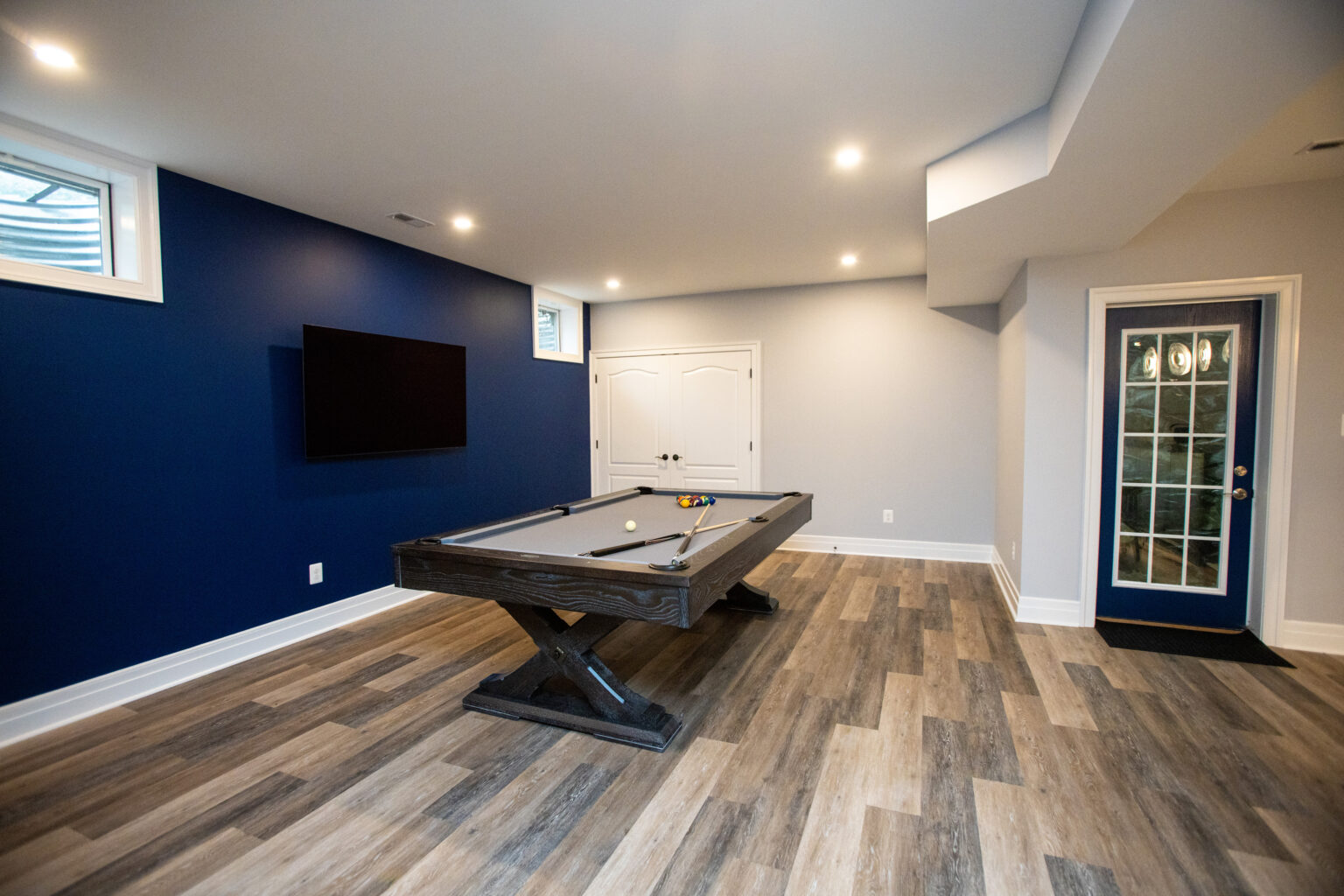 Pool table area and pedestrian door leading outside in this basement.