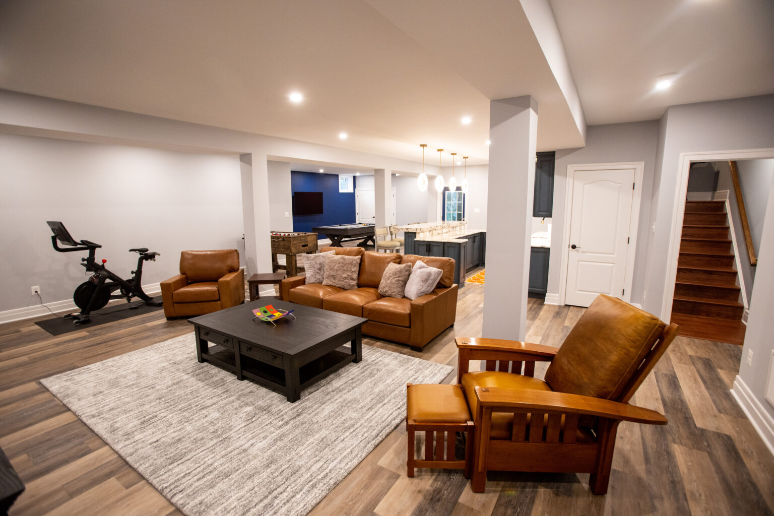 A finished basement with living room, bar, pool table and exercise bike in Herndon, Virginia.