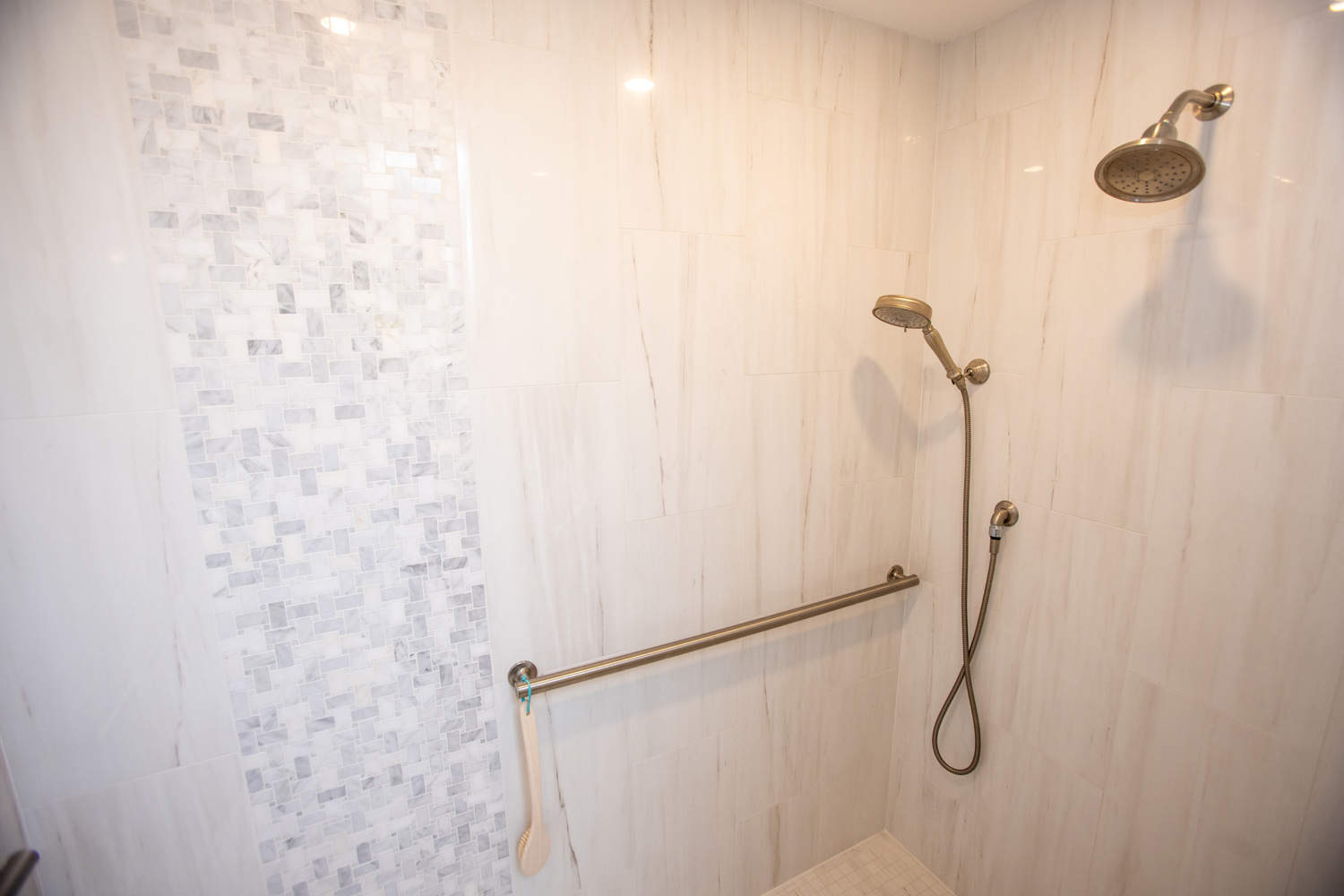 Image by Lesnick Photo Tile shower enclosure with grab bar and spray handle for aging-in-place needs.