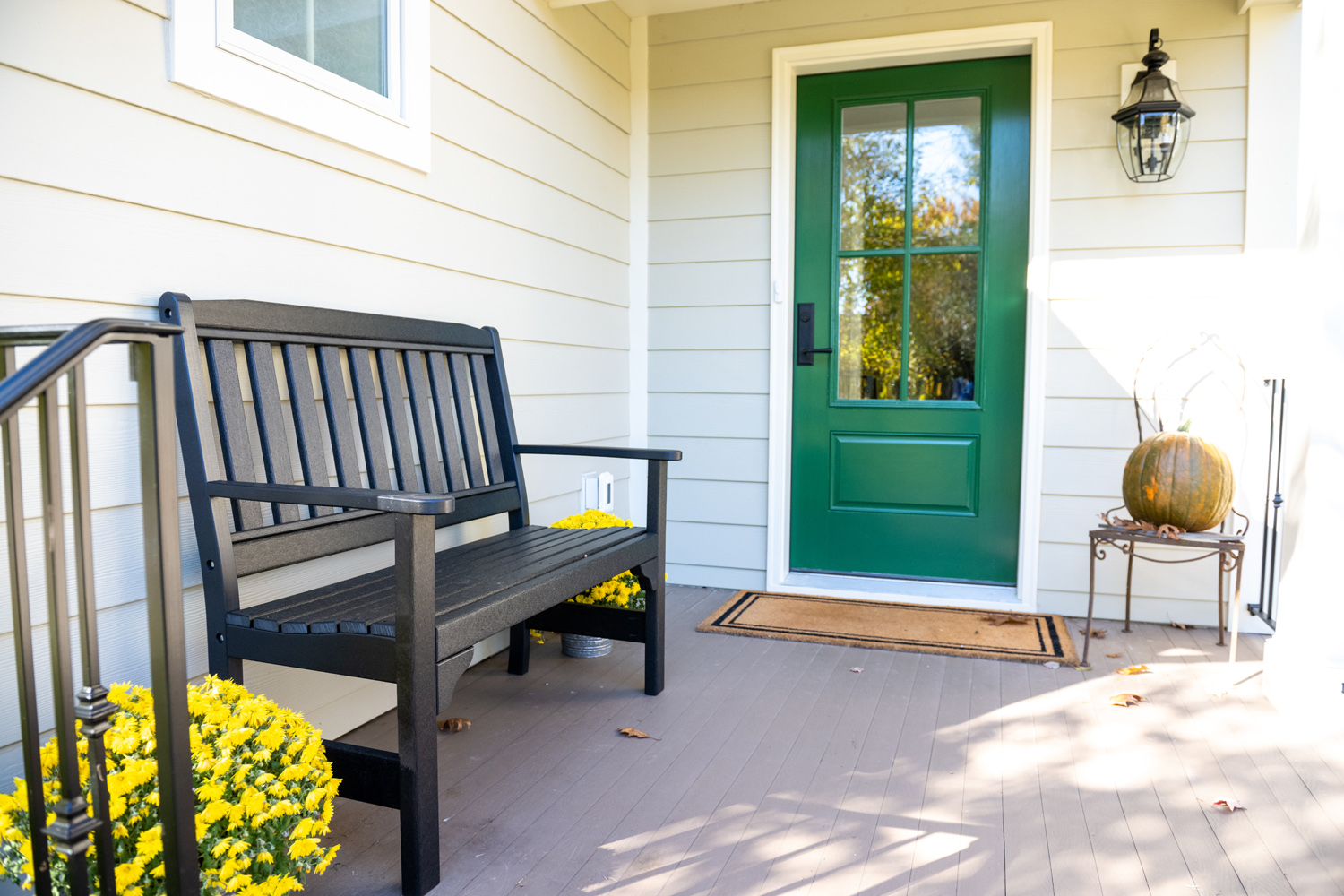Image by Lesnick Photo A black bench on a porch with a green door at the new front entrance of this Great Falls, VA home addition