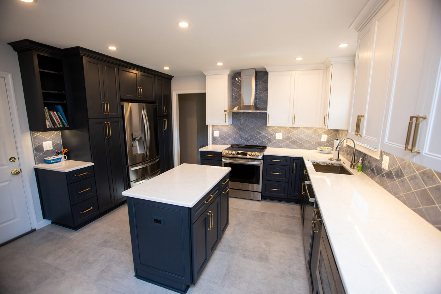 Modern kitchen with black lower cabinets, white upper cabinets, stainless steel appliances, white countertops, central island, and a tiled backsplash.