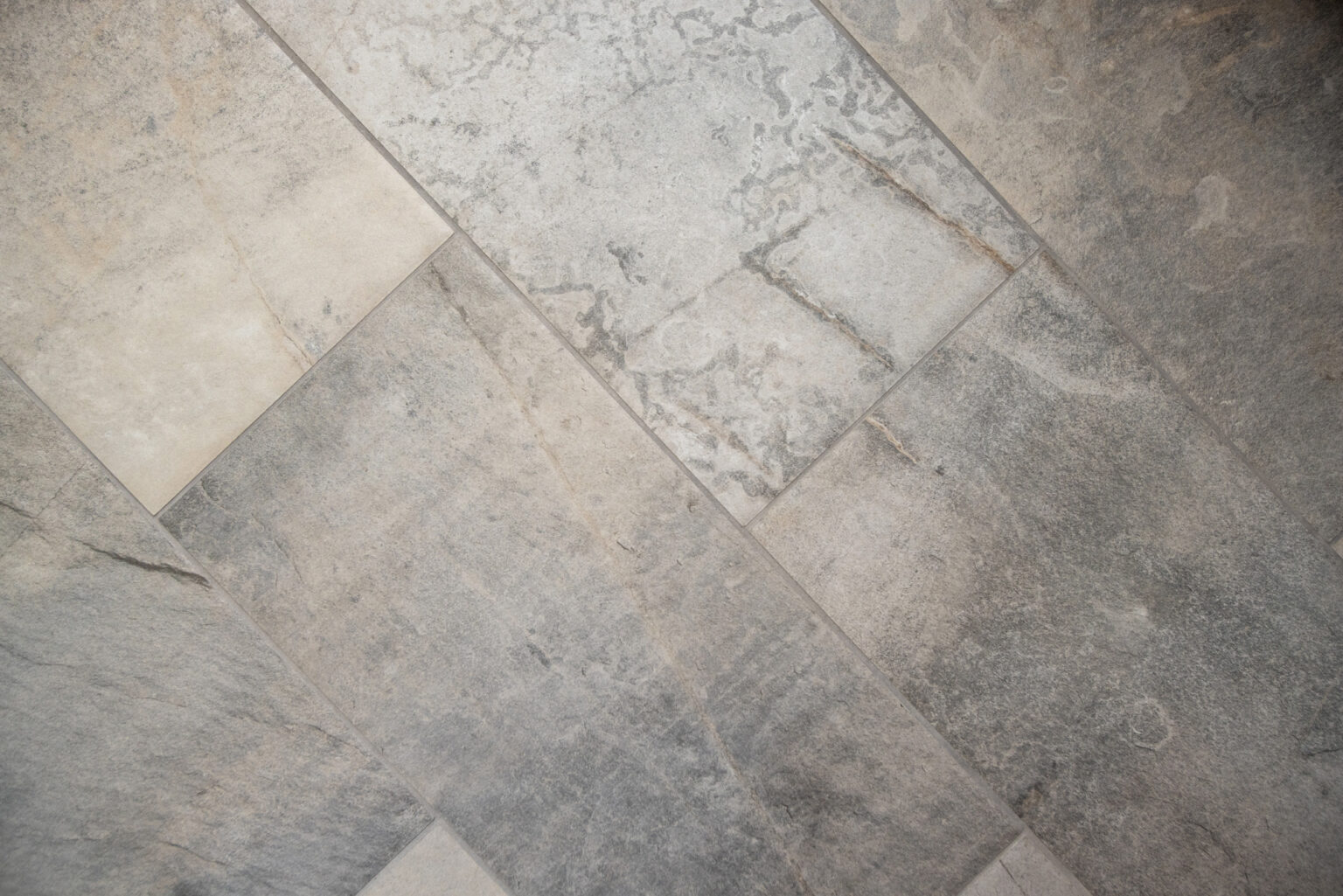 Close-up view of a gray tiled floor with a textured, stone-like appearance and slight color variations.