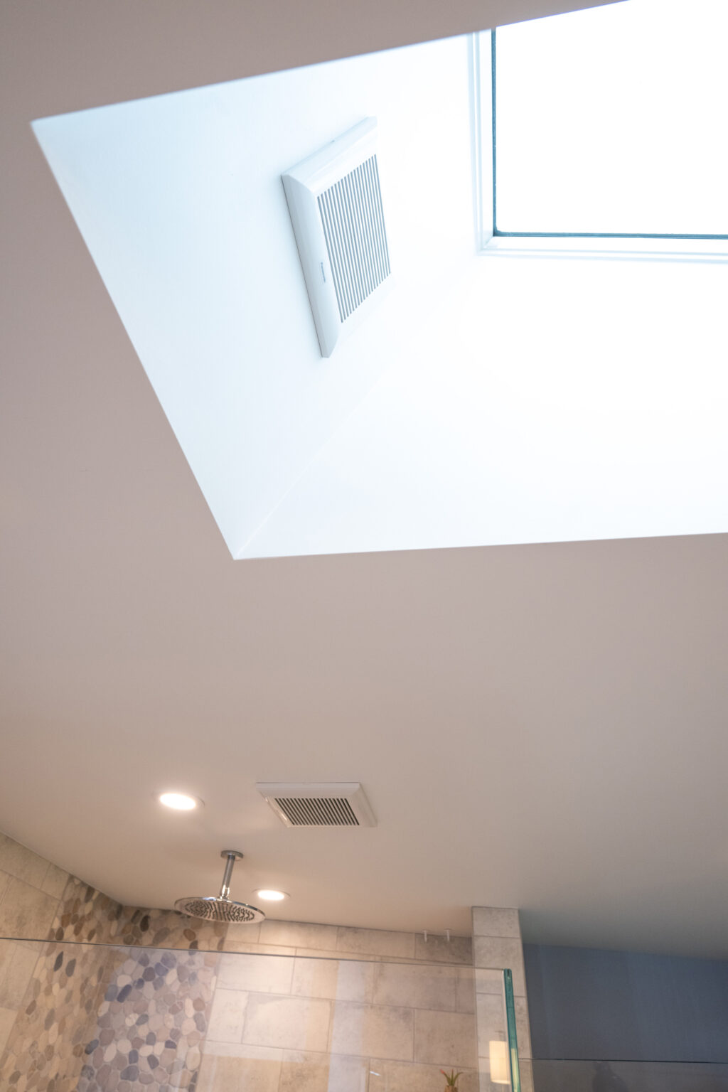 Image by Lesnick Photo Bathroom ceiling with a skylight, vent, recessed lights, and a rainfall showerhead. Walls are decorated with tiles.