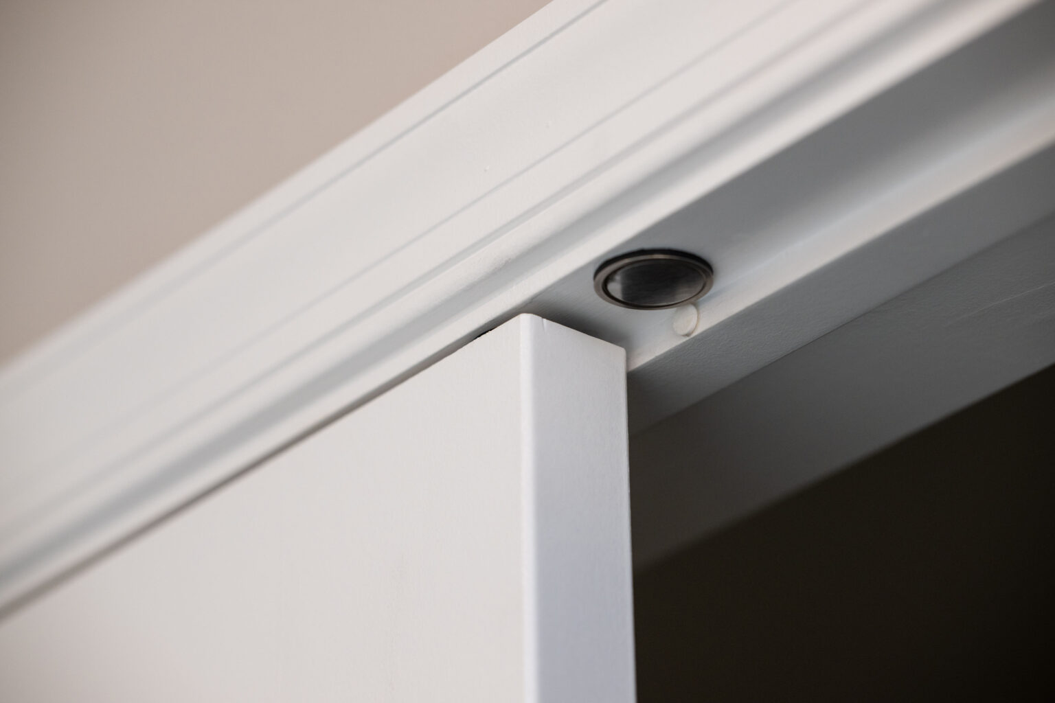 Close-up of a sliding door in its track, with a focus on the upper corner and the track mechanism on the ceiling.