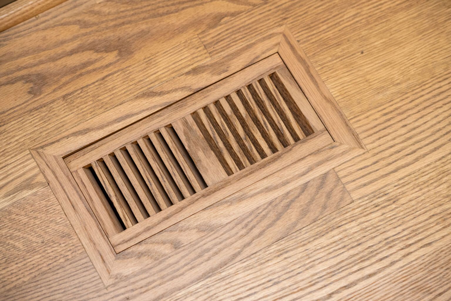 Image by Lesnick Photo A wooden floor vent with horizontal slats is set into a light oak floor.