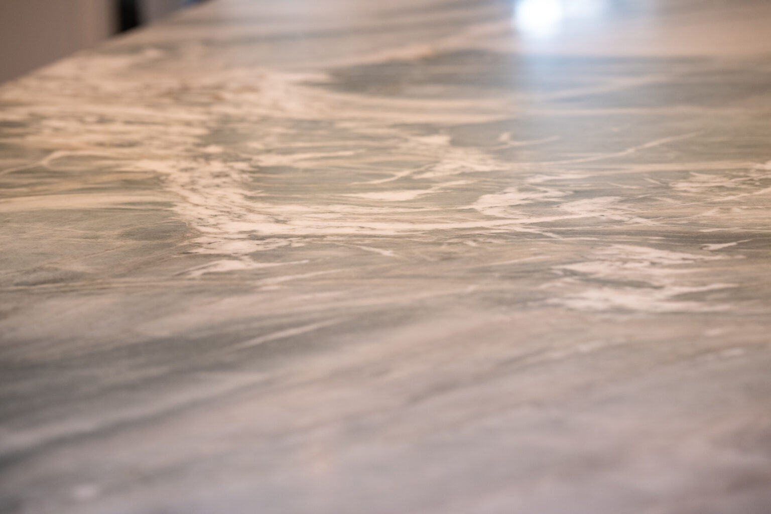 Image by Lesnick Photo Close-up of a marble countertop with a light gray and white swirling pattern.