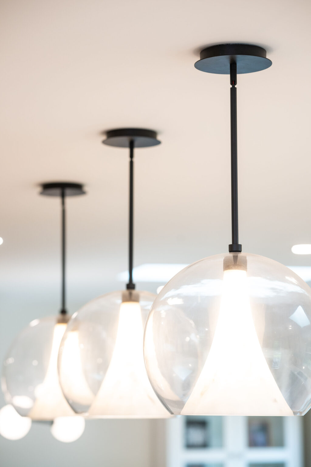 Three modern pendant lights with clear glass globes hang from the ceiling, illuminating the space with a soft glow.