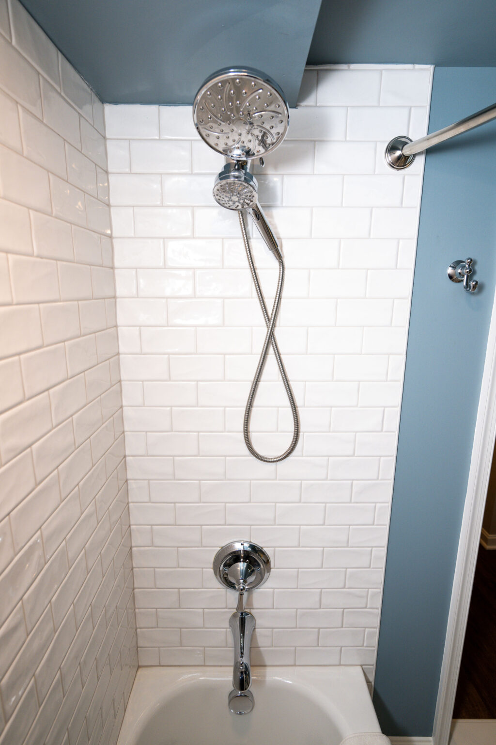 Image by Lesnick Photo Shower with white subway tile walls, chrome showerhead, and faucet above a white bathtub.