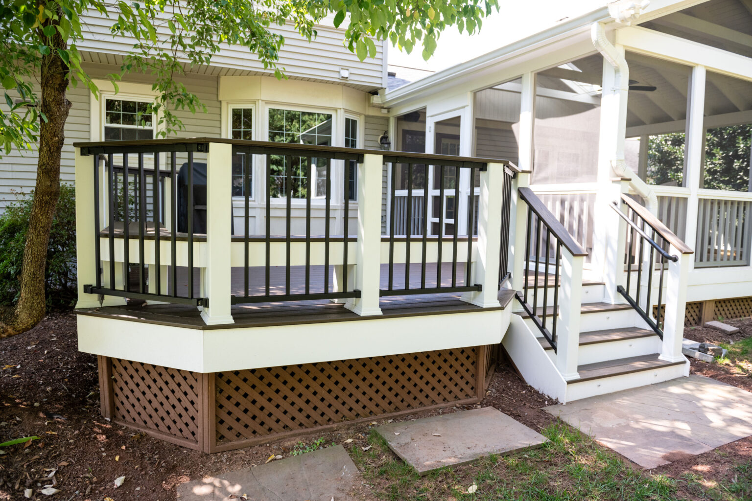 Image by Lesnick Photo Wooden deck attached to a house with black and white railing, steps leading up, and lattice skirting beneath.