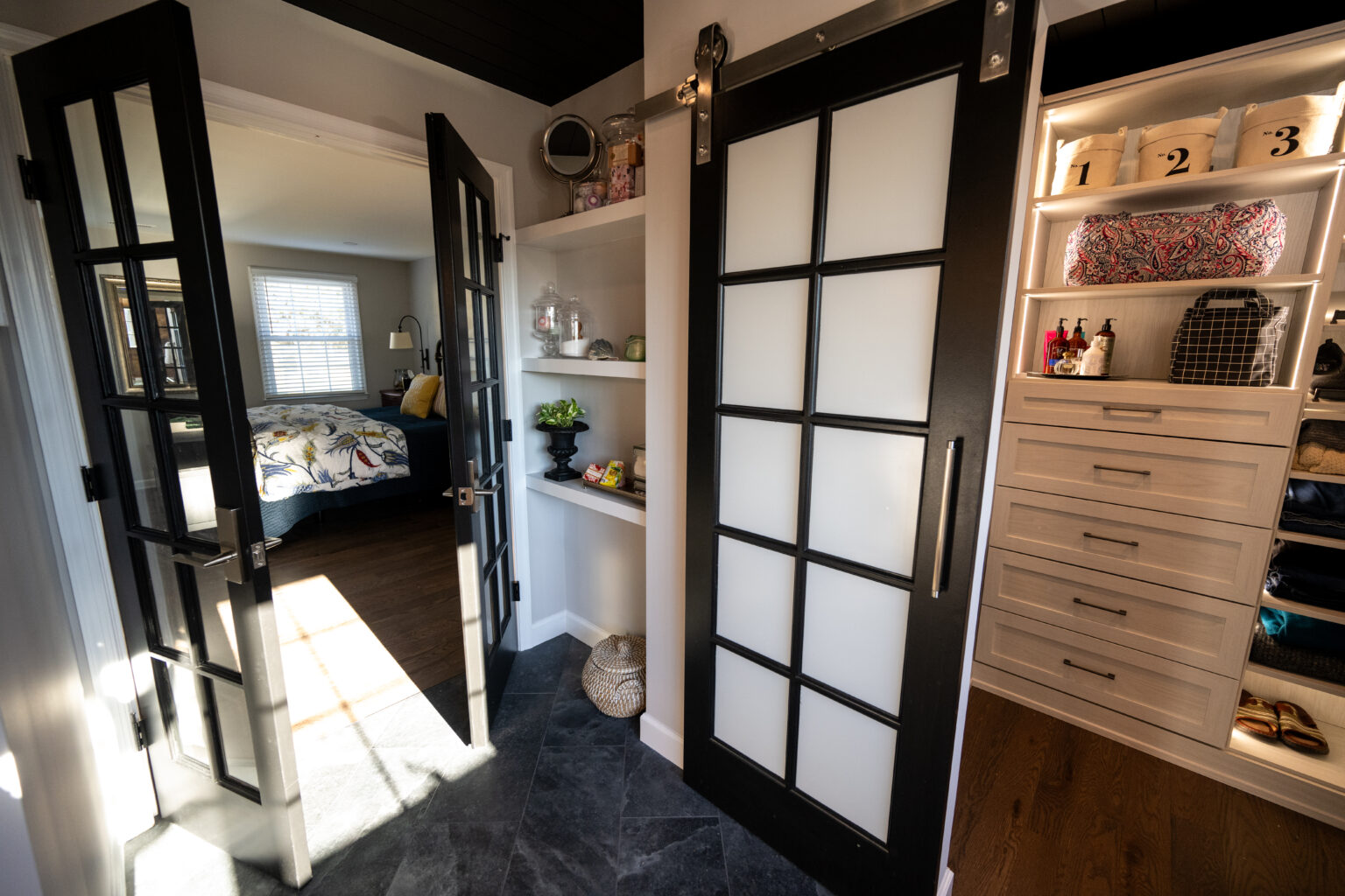 A closet with built-in shelves and drawers, sliding glass doors, and an adjacent bedroom visible through double doors.