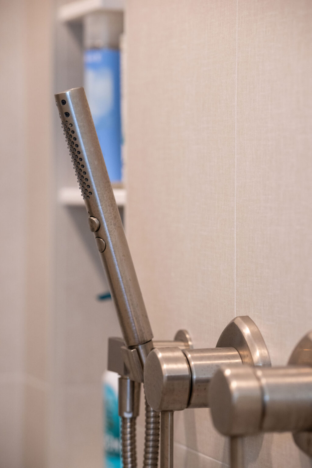 Close-up of a modern showerhead with a hand spray attachment and metal fixtures in a bathroom.