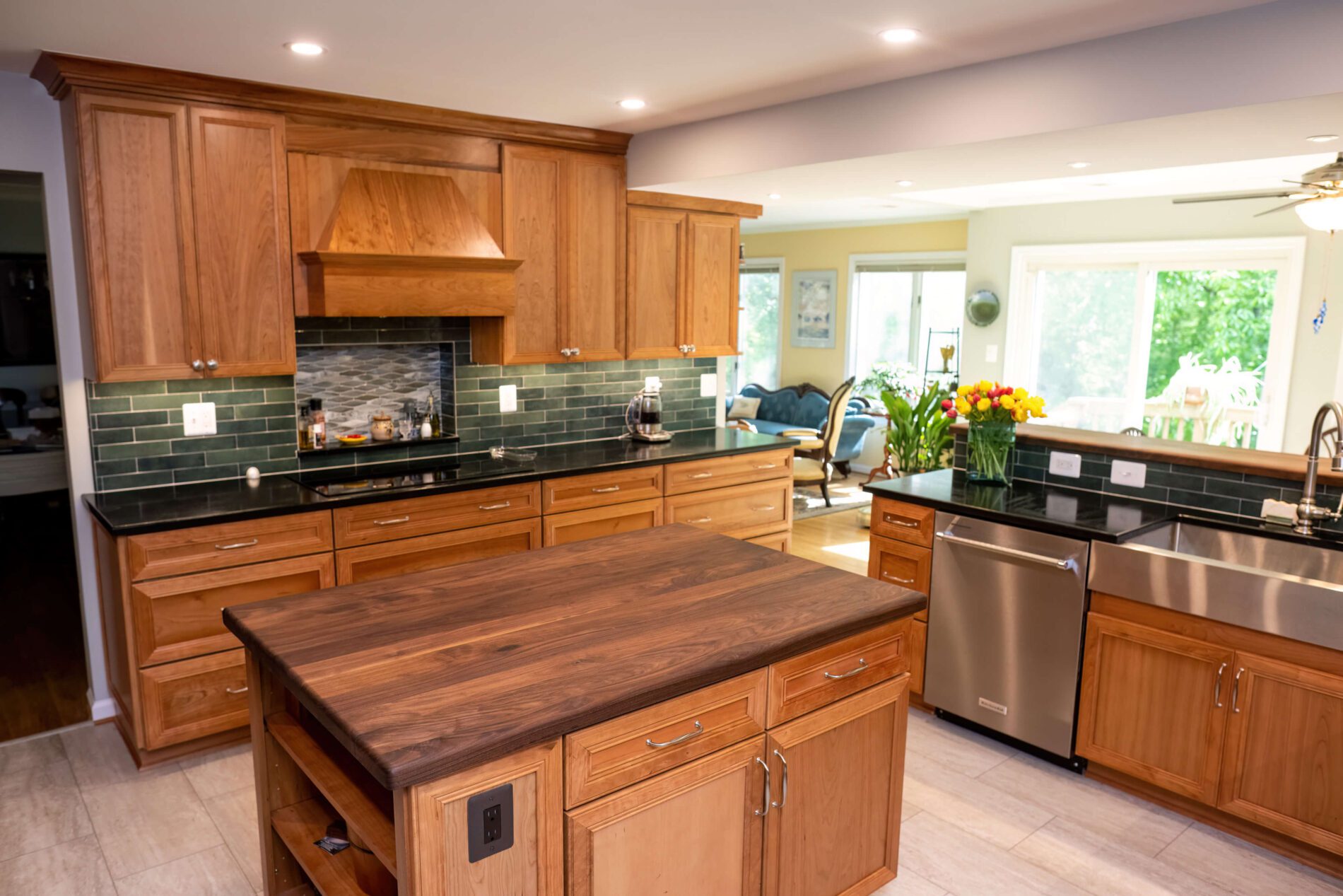Modern kitchen with wooden cabinets, black countertops, a center island, stainless steel appliances, and a vase of flowers near a large window overlooking greenery—an inspiring space if you’re wondering how much does a kitchen remodel cost in northern Virginia.
