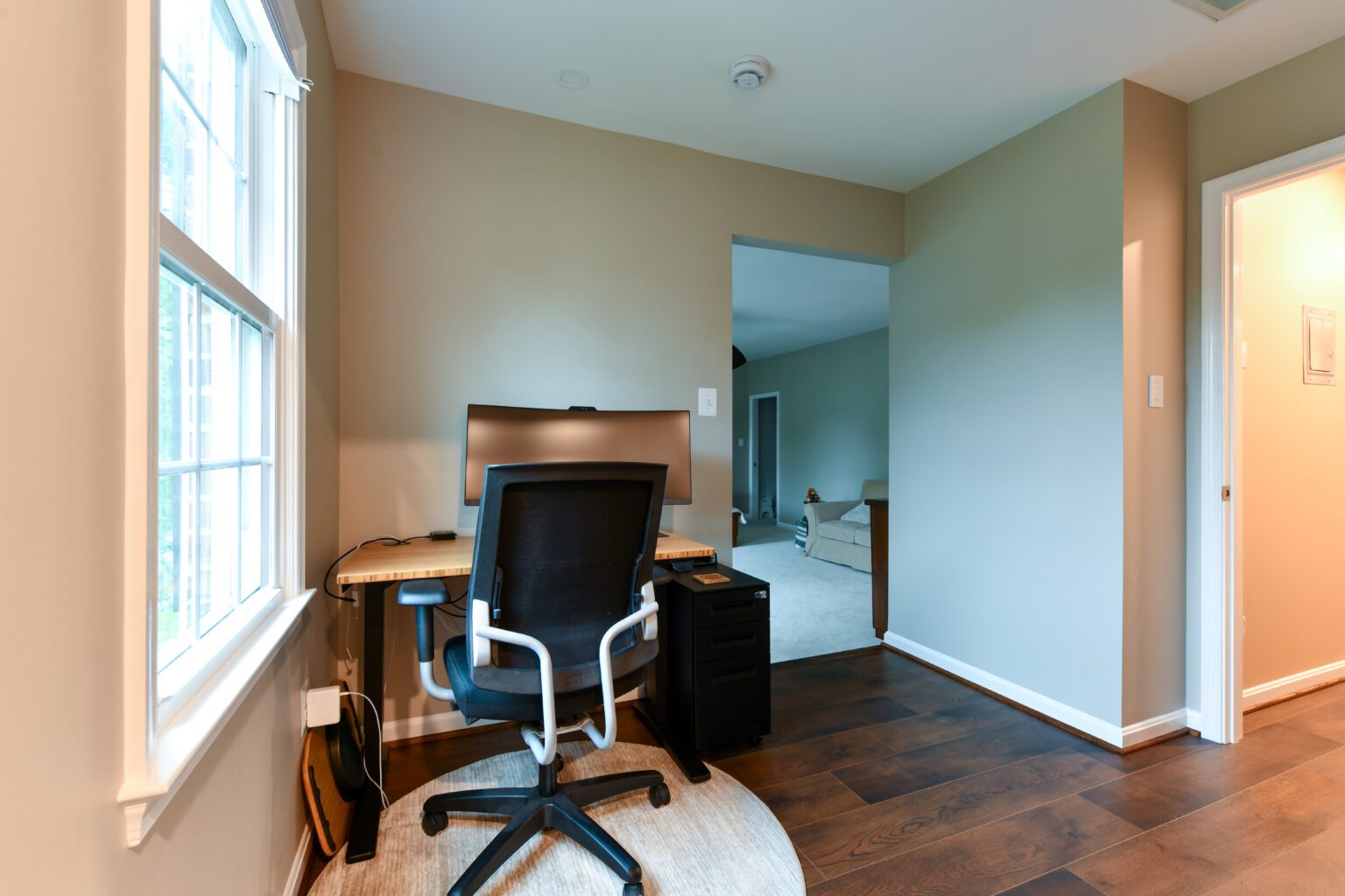 Vienna Primary En-suite and Laundry (17) A home office setup with a computer on a wooden desk, black office chair, and a small filing cabinet. The room has hardwood floors and a window letting in natural light.