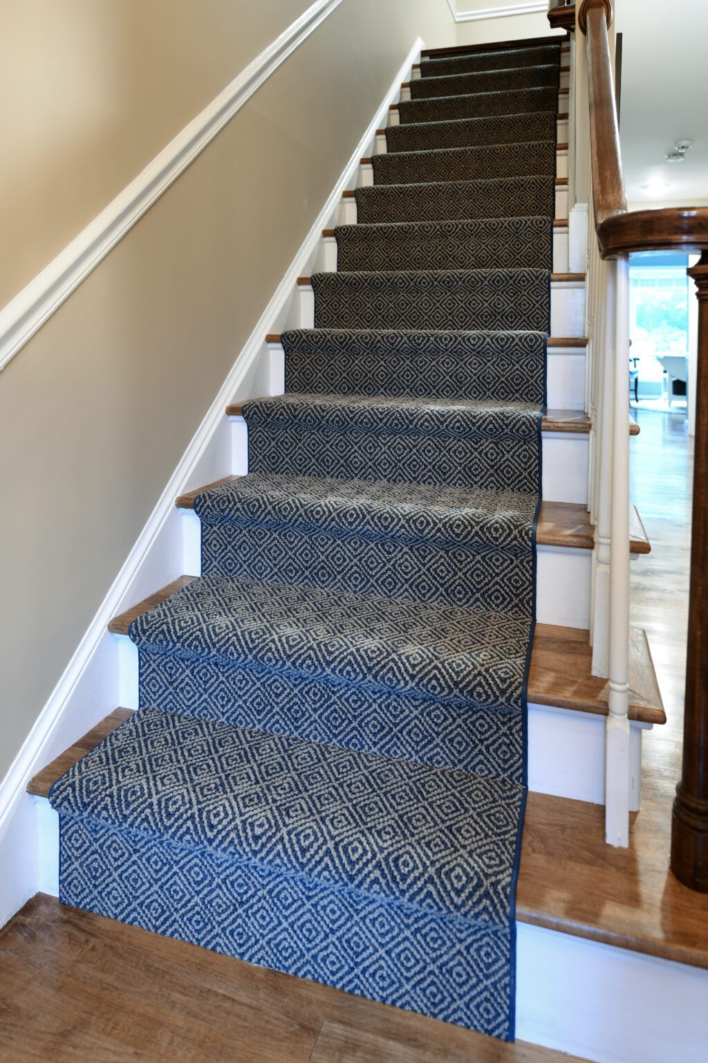 Vienna Primary En-suite and Laundry (27) Carpeted staircase with a blue and white geometric runner, wooden steps, white risers, and brown handrails in a well-lit home interior.