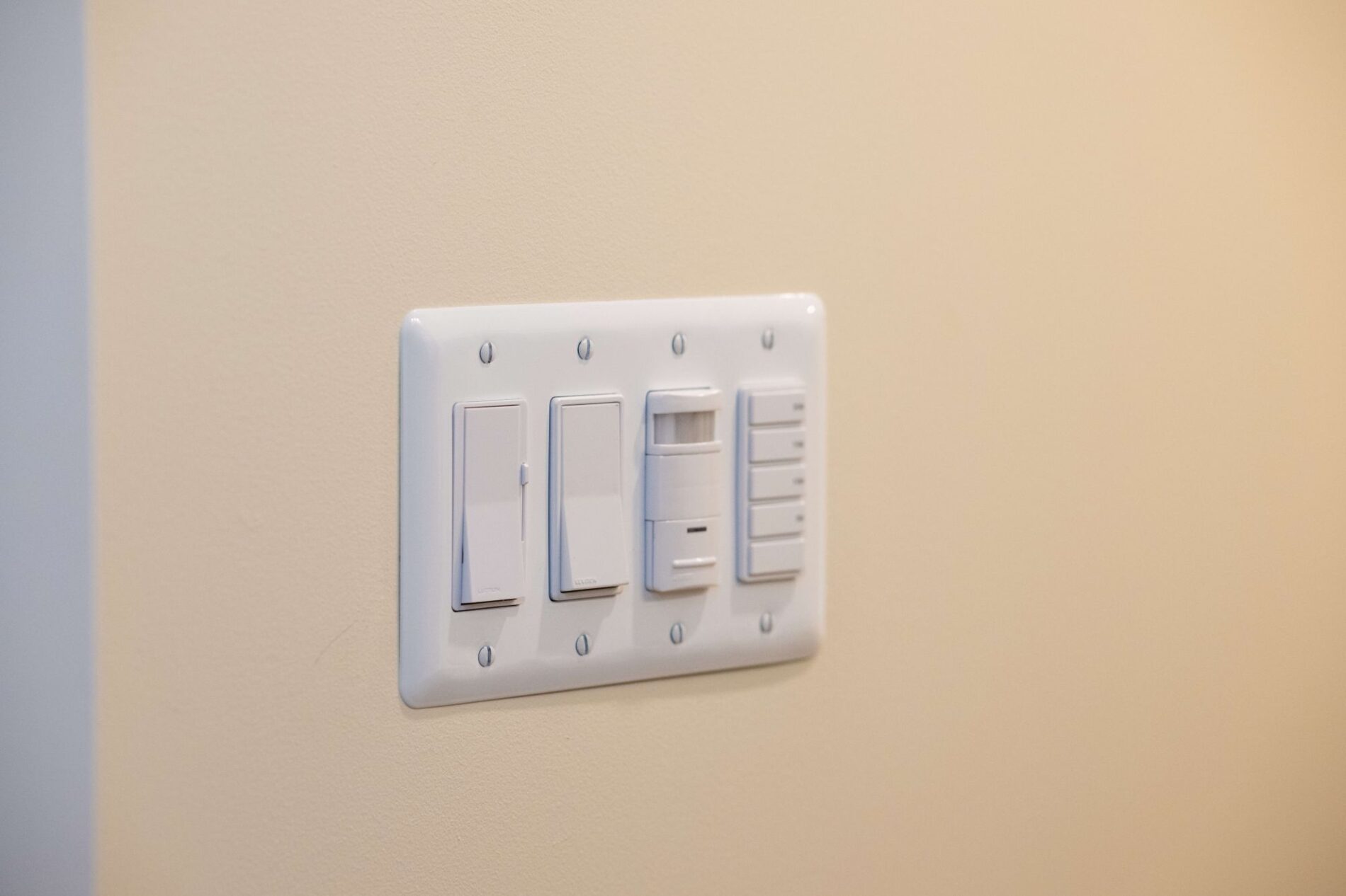 A white switch plate with five different switches and buttons, designed for convenience, is mounted on a beige wall—ideal among aging in place products.
