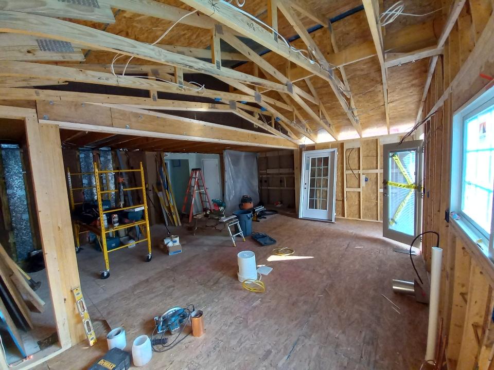 Interior of a house under construction with exposed wooden framework, tools, ladders, and building materials scattered on the floor. If you’re wondering where to stay during a renovation like this, temporary accommodations may be necessary.